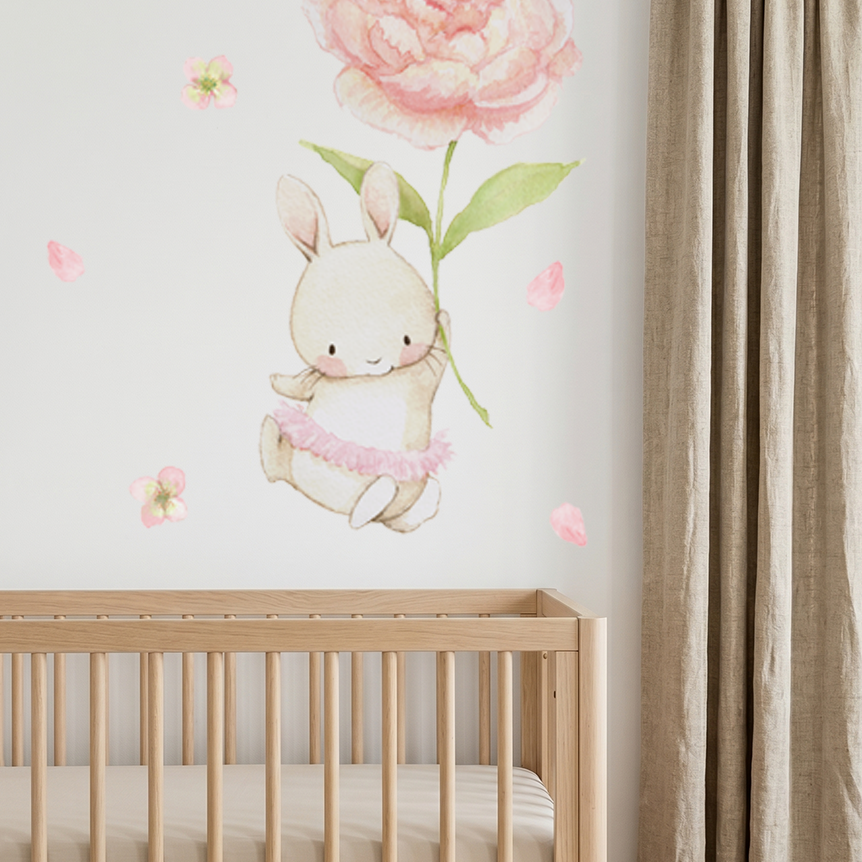 Watercolor bunny holding a pink peony fabric wall decal installed above a wooden crib in a nursery