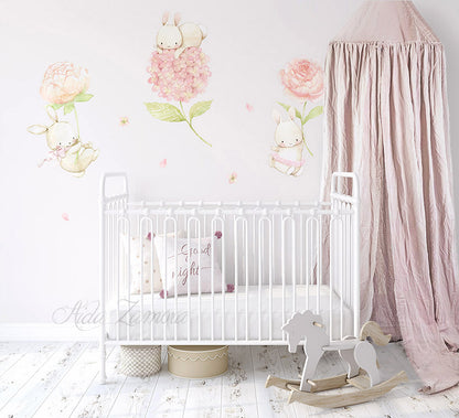 Watercolor floral bunnies fabric wall decals installed on a wall above a white metal baby crib with pink canopy