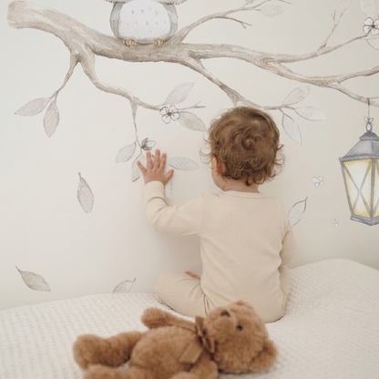 Baby touching a watercolor tree branch fabric wall decal set with owl and lantern in a cozy neutral nursery