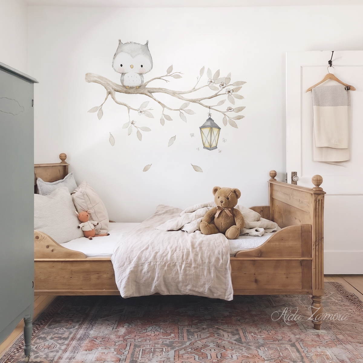 Watercolor owl on a tree branch fabric wall decal set installed above a wooden toddler bed in a neutral nursery