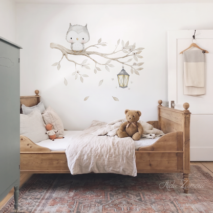 Watercolor owl on a tree branch fabric wall decal set installed above a wooden toddler bed in a neutral nursery