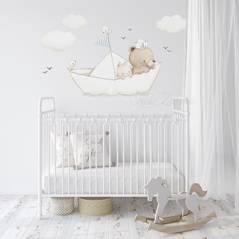Paper boat fabric wall decal featuring teddy bear sailor, bunny, and clouds arranged on a white wall above a vintage white metal crib