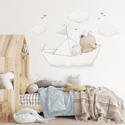 Paper boat fabric wall decal featuring watercolor bear sailor, bunny, and clouds above a toddler wooden house frame bed with pastel blue and beige bedding